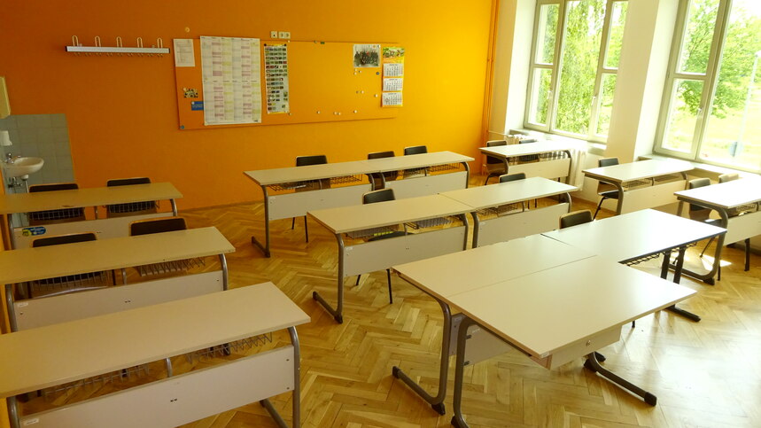 Ein leeres Klassenzimmer mit warmen gelben Wänden und Tischen und Stühlen