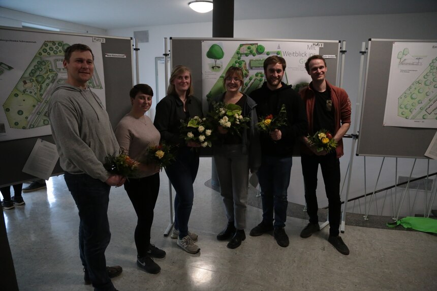 Menschen mit Blumensträußen vor aufgehängten Entwürfen