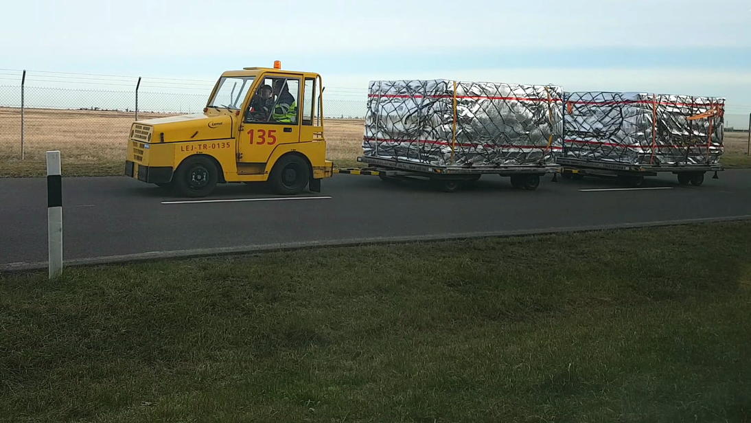 Eingetroffene Ware wird auf dem Rollfeld transportiert