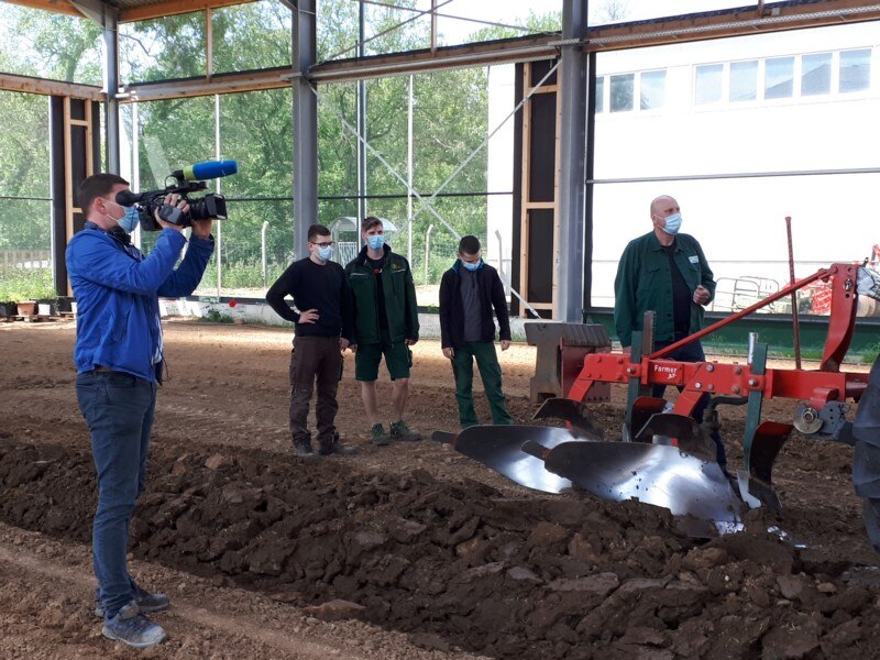 MDR-Reporter filmt in der neuen Trainingshalle das Pflügen mit Traktor durch Azubis.