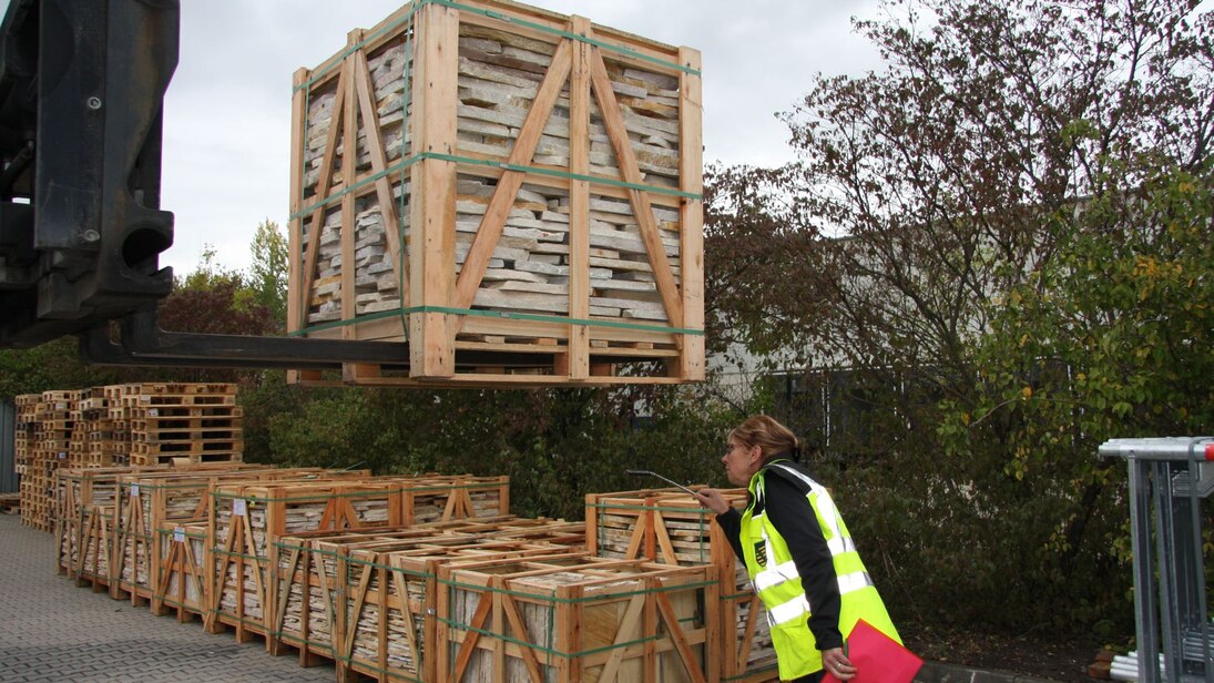 Natursteinwaren in Holzverpackung werden mit Hilfe eines Spiegels auf Schaderreger kontrolliert