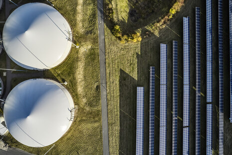 Eine Luftbildaufnahme von 2 Fermentern einer Biogasanlage sowie Solarmoule die daneben stehen