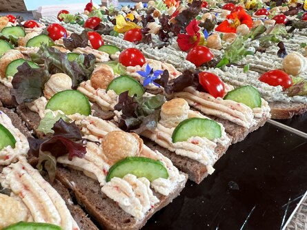 Schnittchen auf Tablett mit Aufstrich, dekoriert mit Gemüse und Blüten