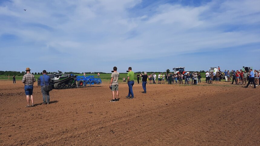 Ein Feldroboter arbeitet auf dem Feld und viele Besucher ibeobachten die autonome Bearbeitung