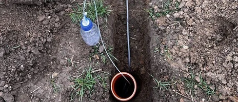 Versuchsaufbau mit Flasche, Schlauch und Graben